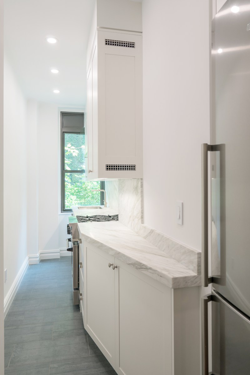 NYC prewar kitchen renovation featuring  classic white contemporary custom cabinet design, grounded with a dark grey porcelain floor